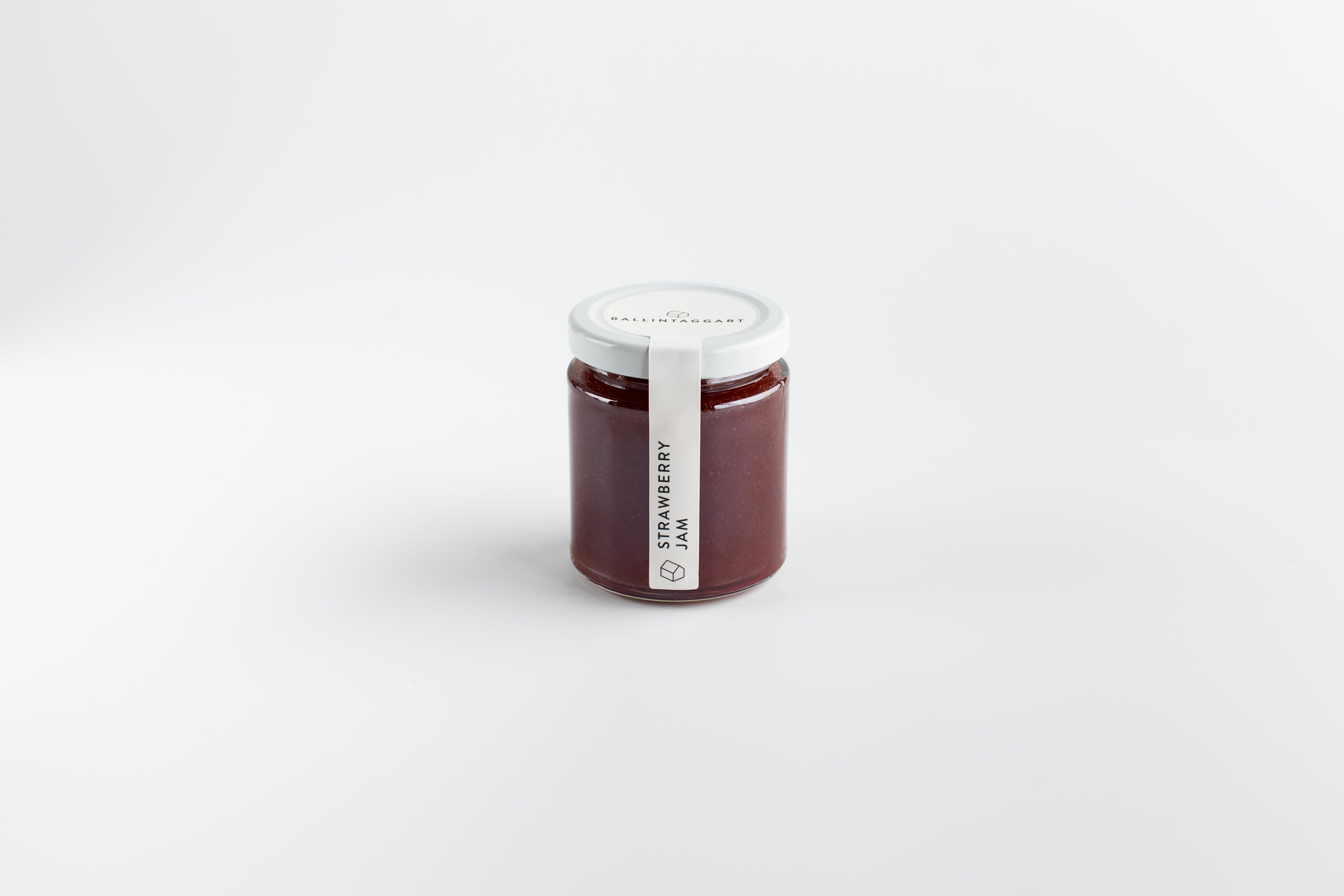 Jar of strawberry jam with a white label on a light gray background