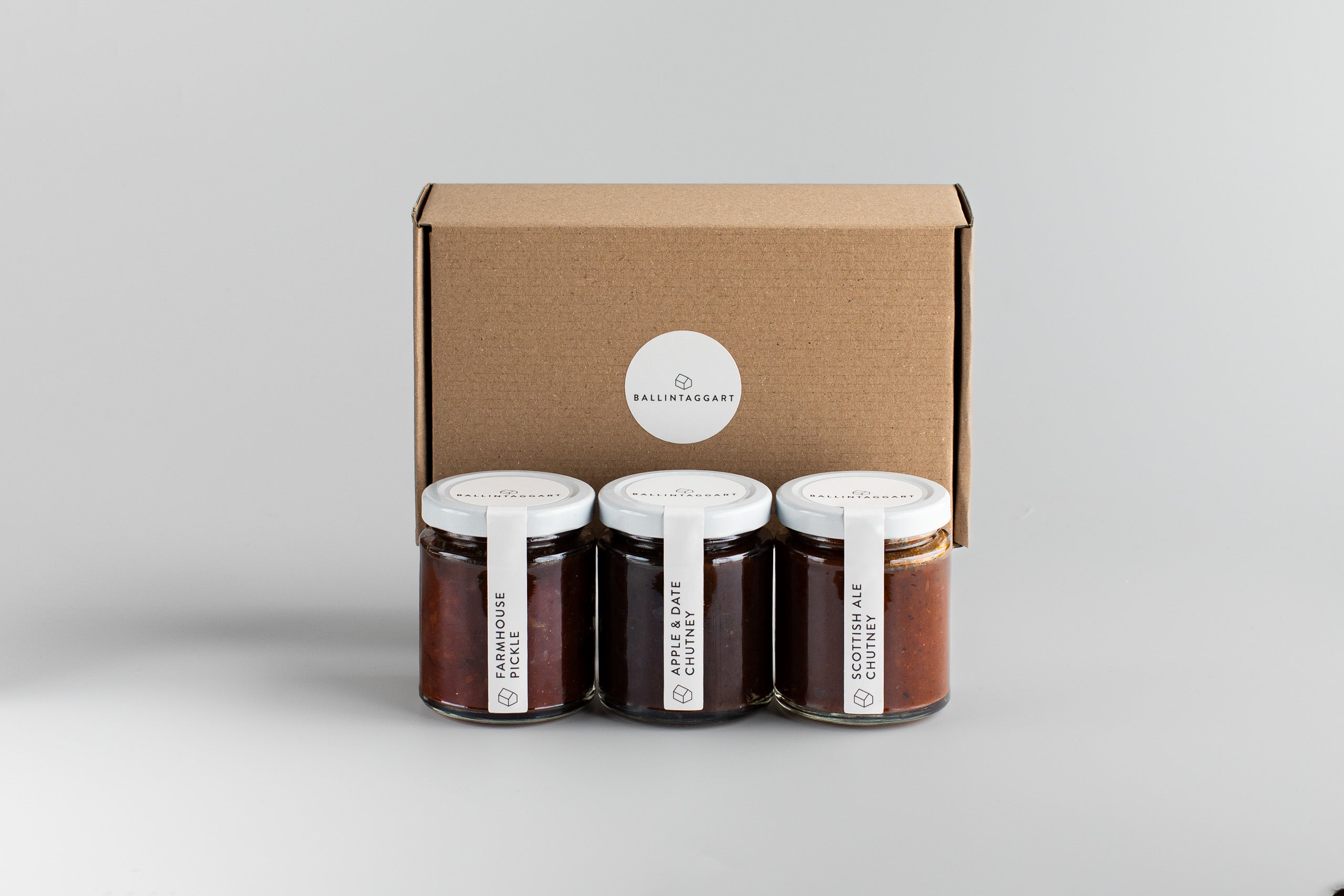 Three jars of chutney with a cardboard box labeled Ballintaggart on a light gray background