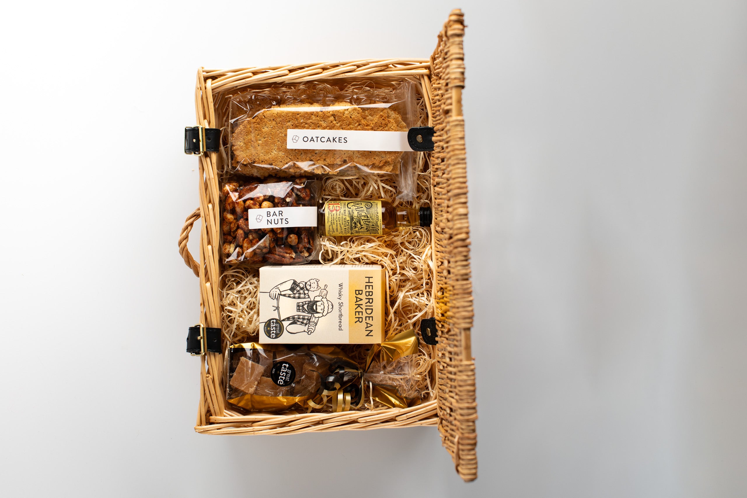 Wicker gift basket with various items including a bottle labeled on a light gray background