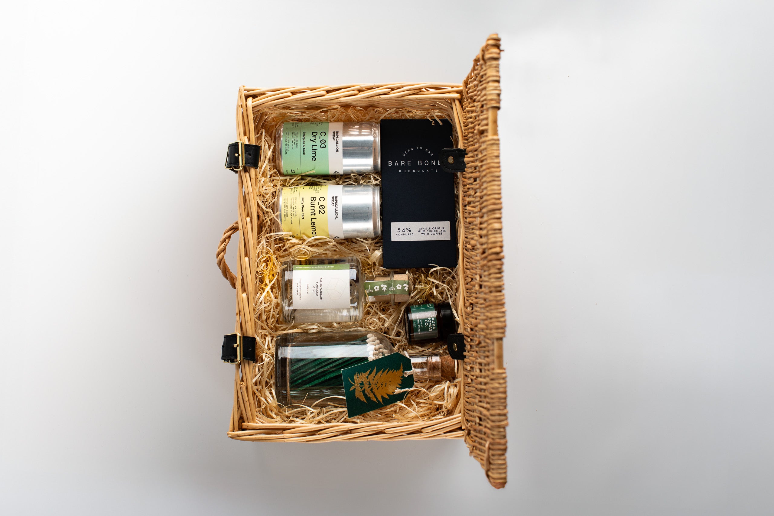 Set of gin and soda bottles in a wicker basket on a white background