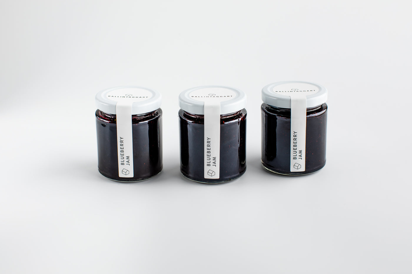 Three jars of blueberry jam on a white background