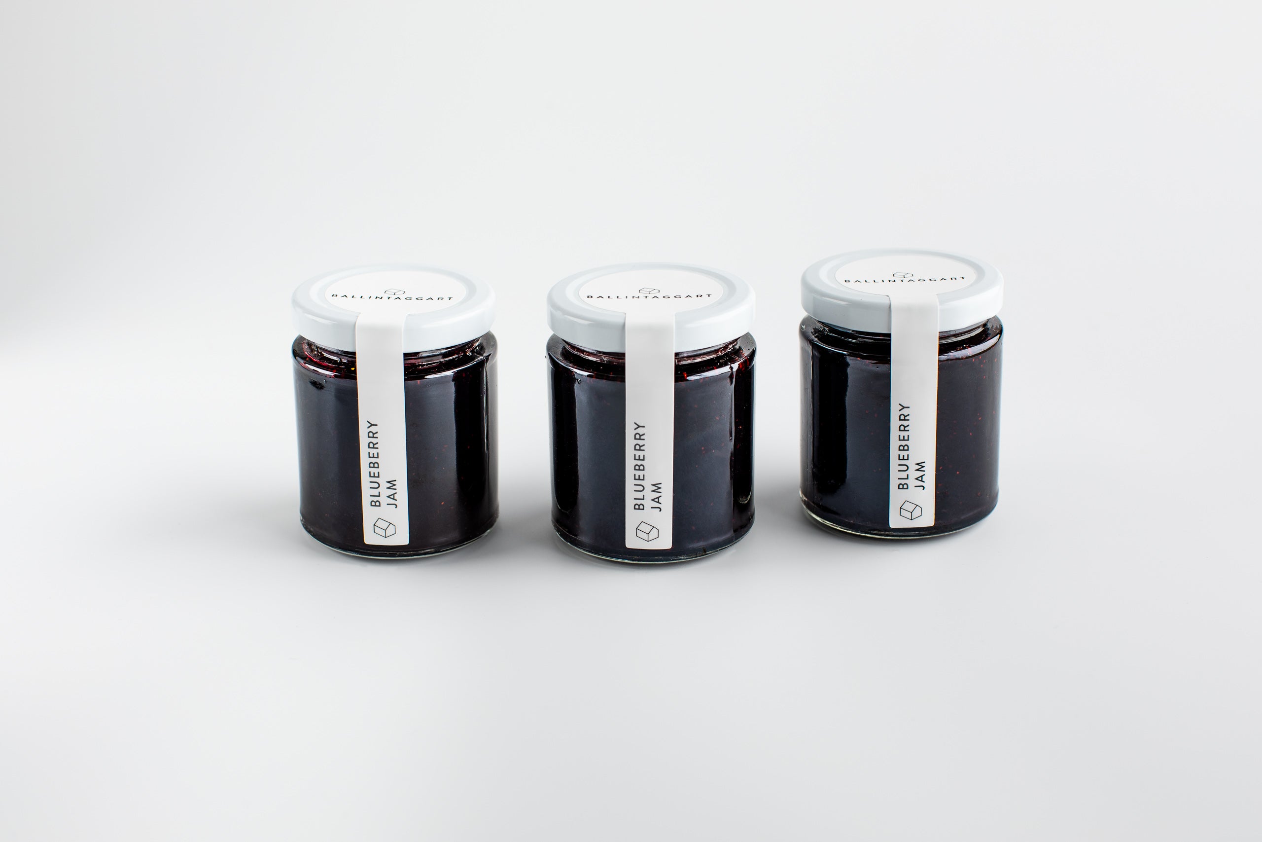 Three jars of blueberry jam on a white background