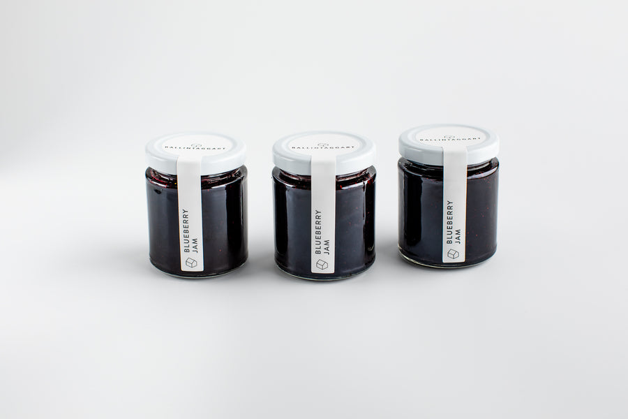 Three jars of blueberry jam on a white background