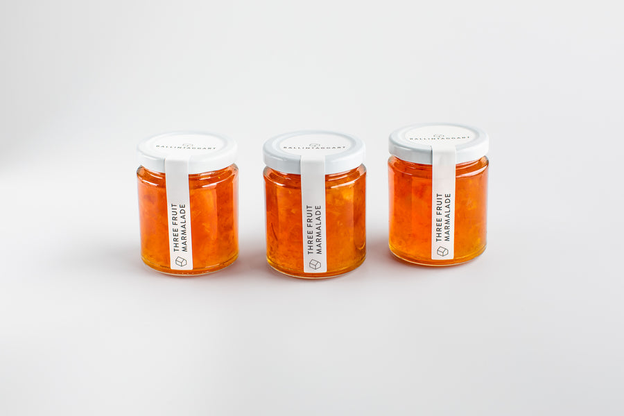 Three jars of marmalade with white lids on a light grey background