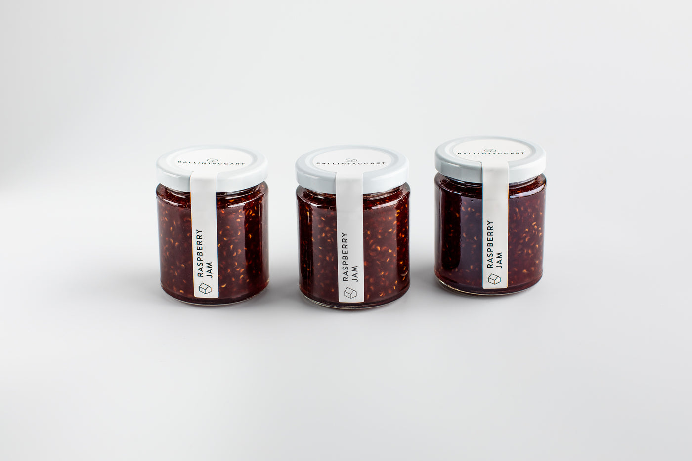 Three jars of raspberry jam on a white background