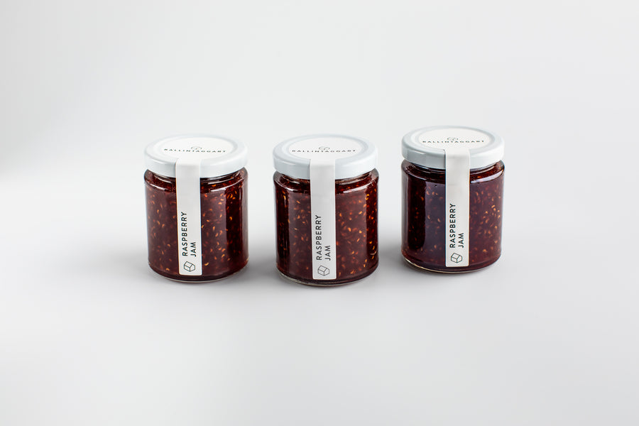 Three jars of raspberry jam on a white background