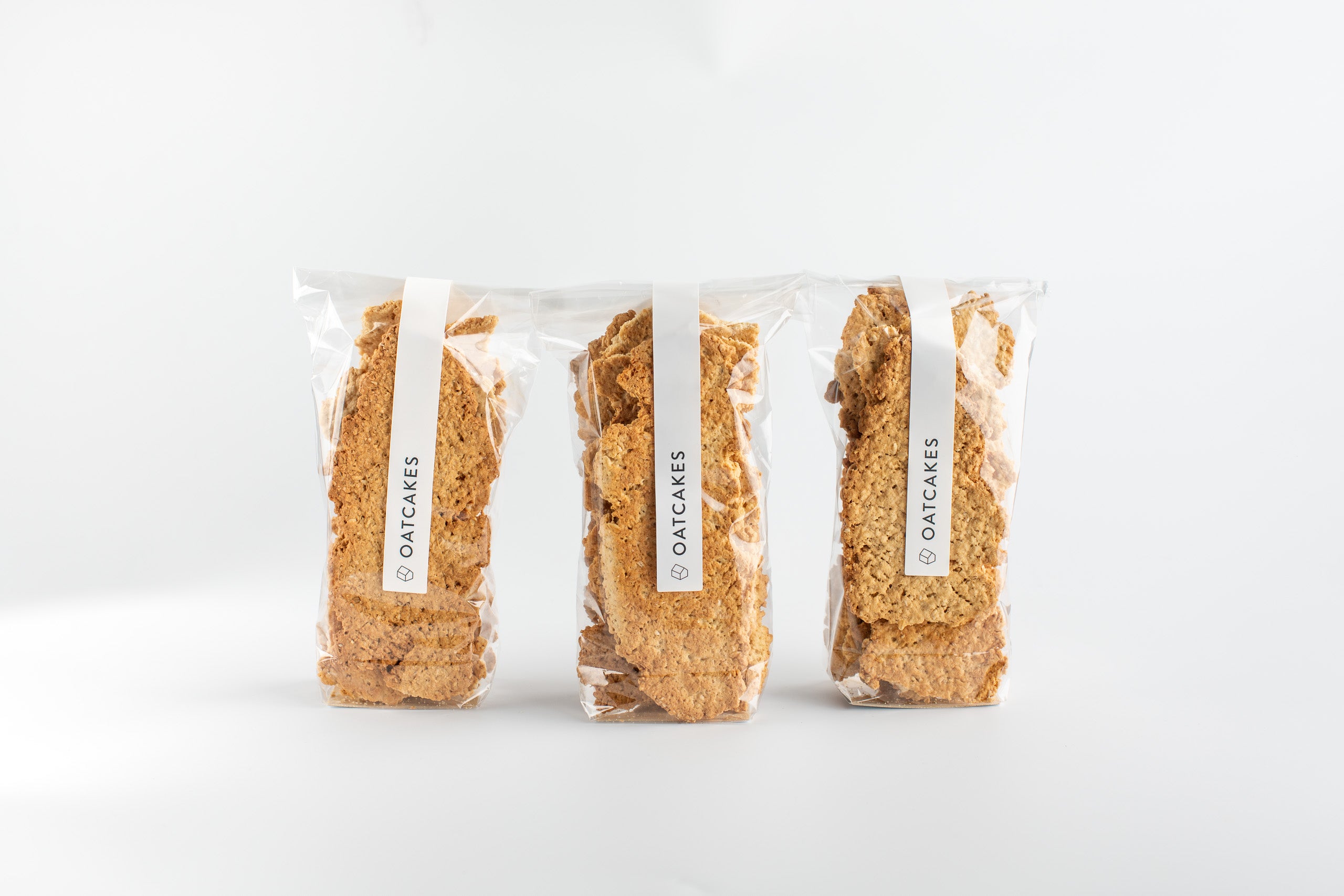 Three packages of oatcakes on a white background