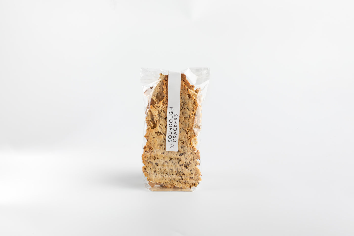 Bag of sourdough crackers with a white label on a light gray background