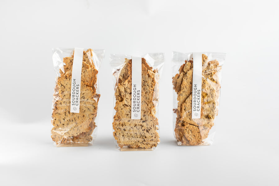 Three packages of sourdough crackers on a white background