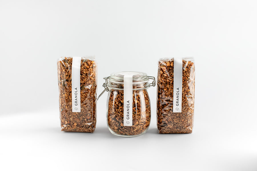 One jar of granola with two bags of granola and labels on a white background