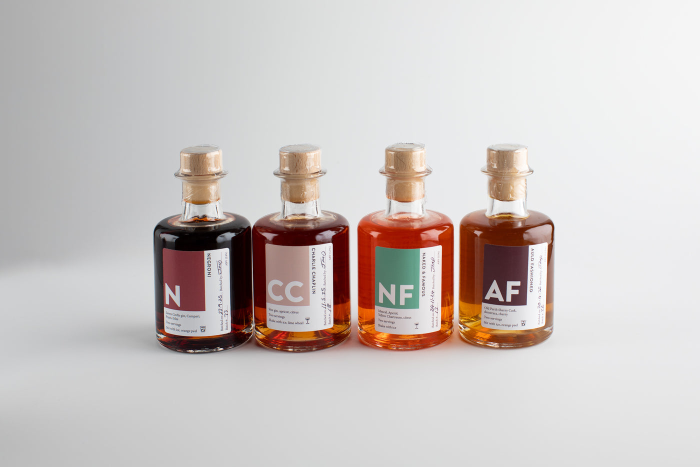 Four small bottles with cork stoppers on a light gray background