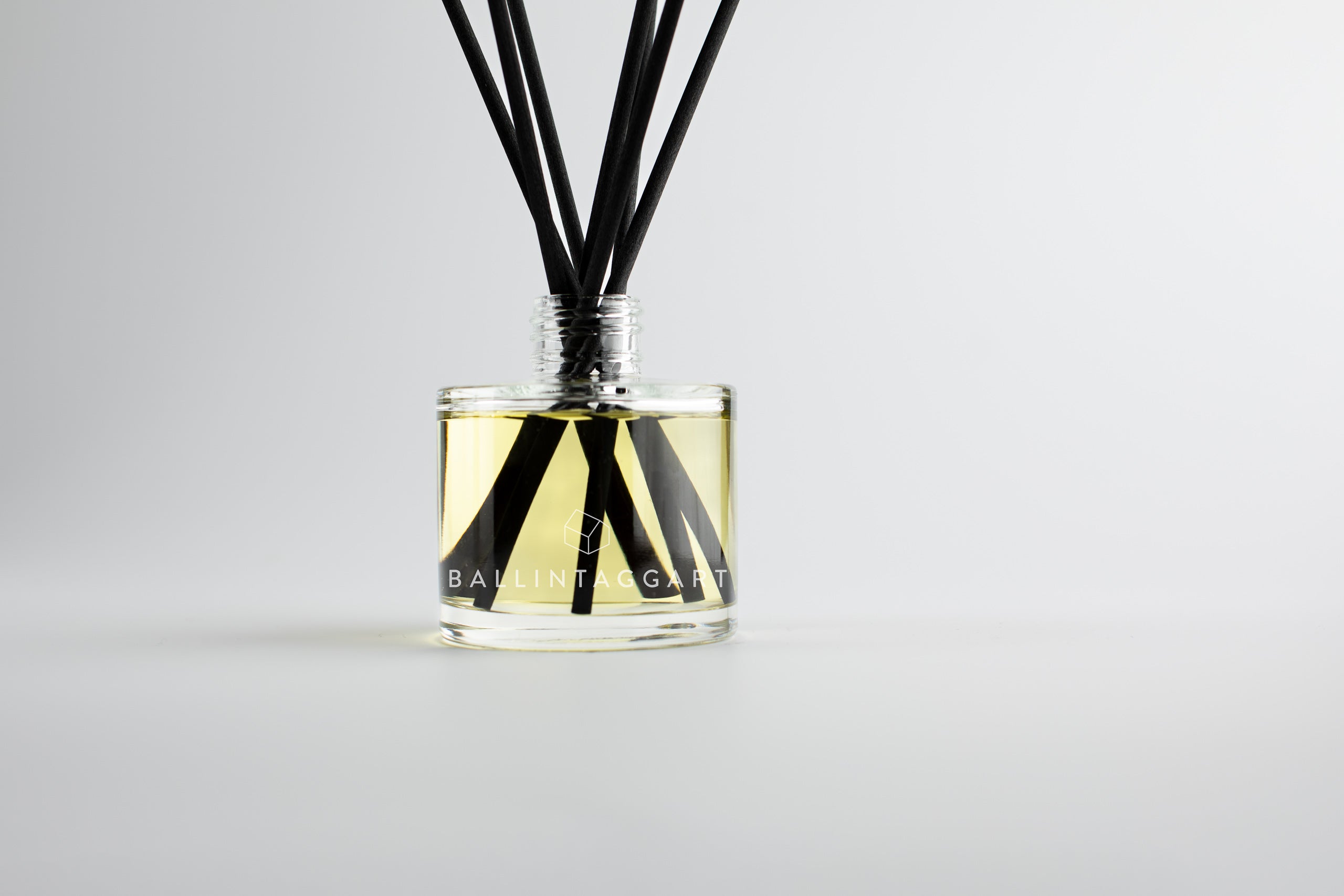 Bottle of Ballintagagrt reed diffuser with black sticks on a light gray background