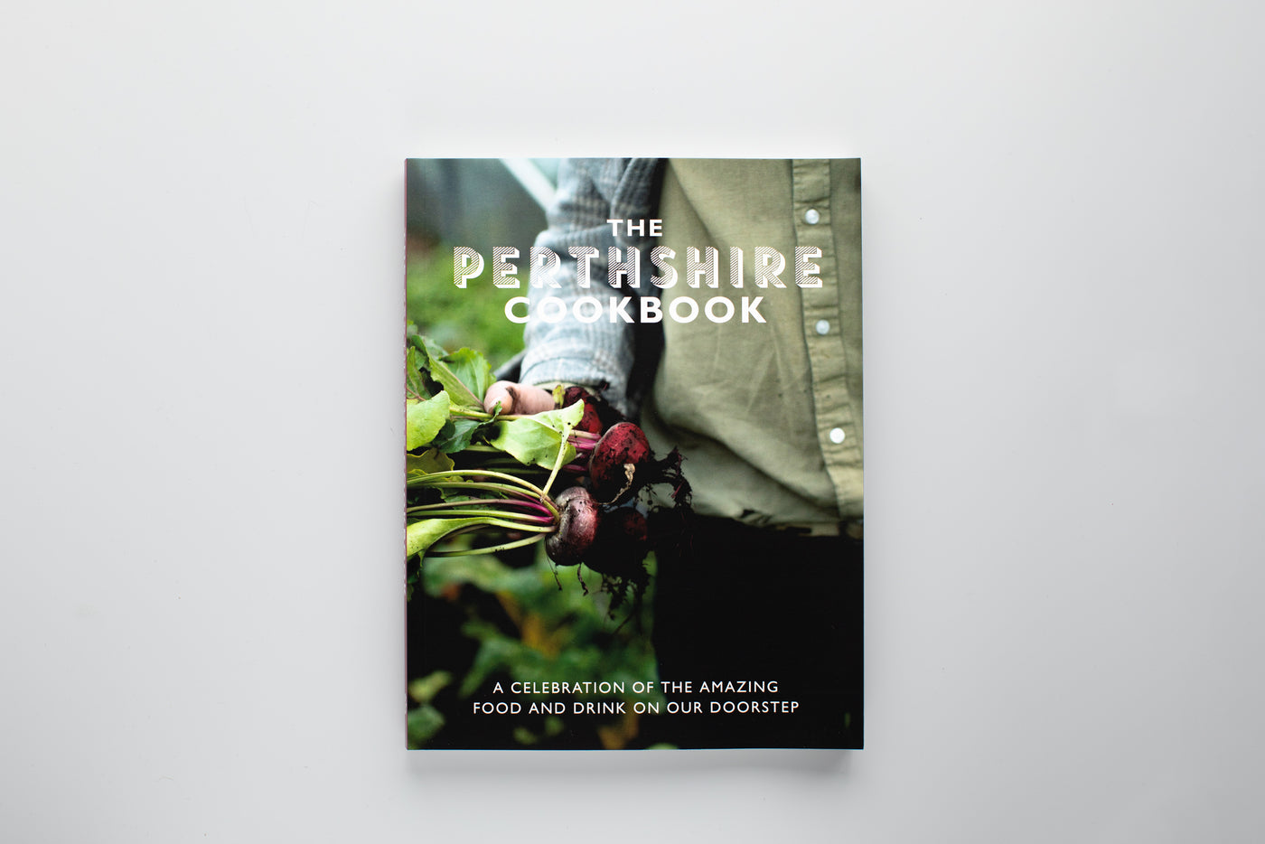 Book cover of 'The Perthshire Cookbook' with a person holding plants on a white background
