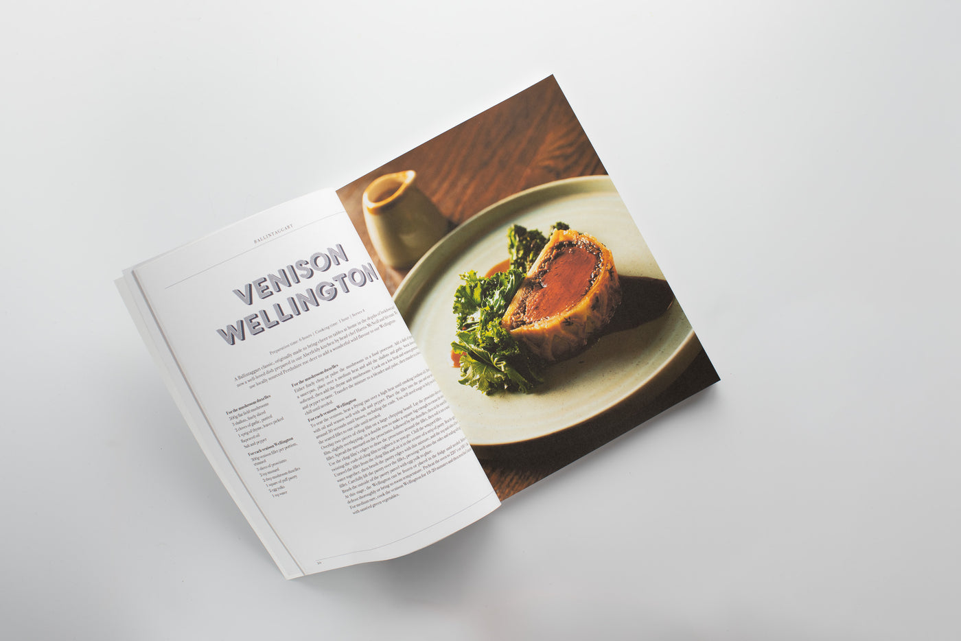 Open cookbook showing a recipe for Venison Wellington on a white surface