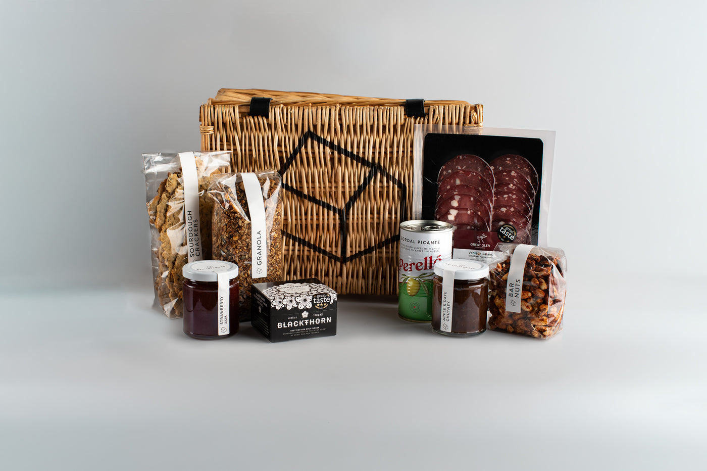 Assorted food items including a woven basket, jars, and packages on a light gray background
