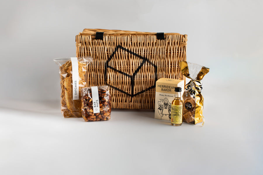 Wicker basket with various items including a bottle and packets on a white background