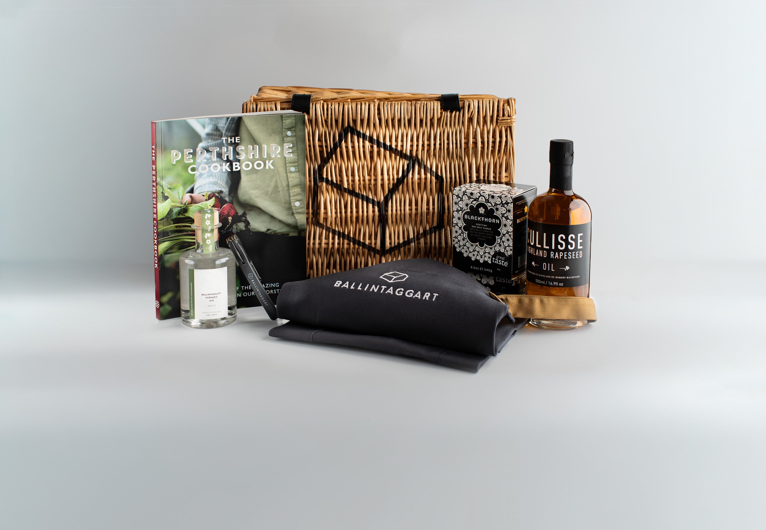 Gift basket with a bottle of Ballinaggart whiskey, a book, and other items on a light grey background