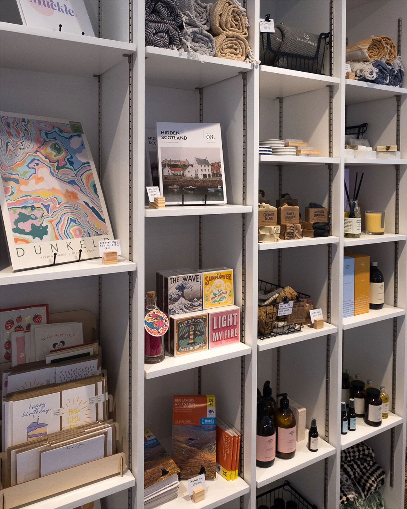 Shelves with various items including books, bottles, and decorative objects in a store setting.