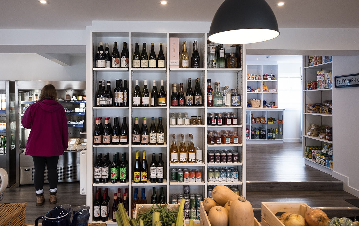 Wine store interior with shelves stocked with various bottles and a person in a red coat.