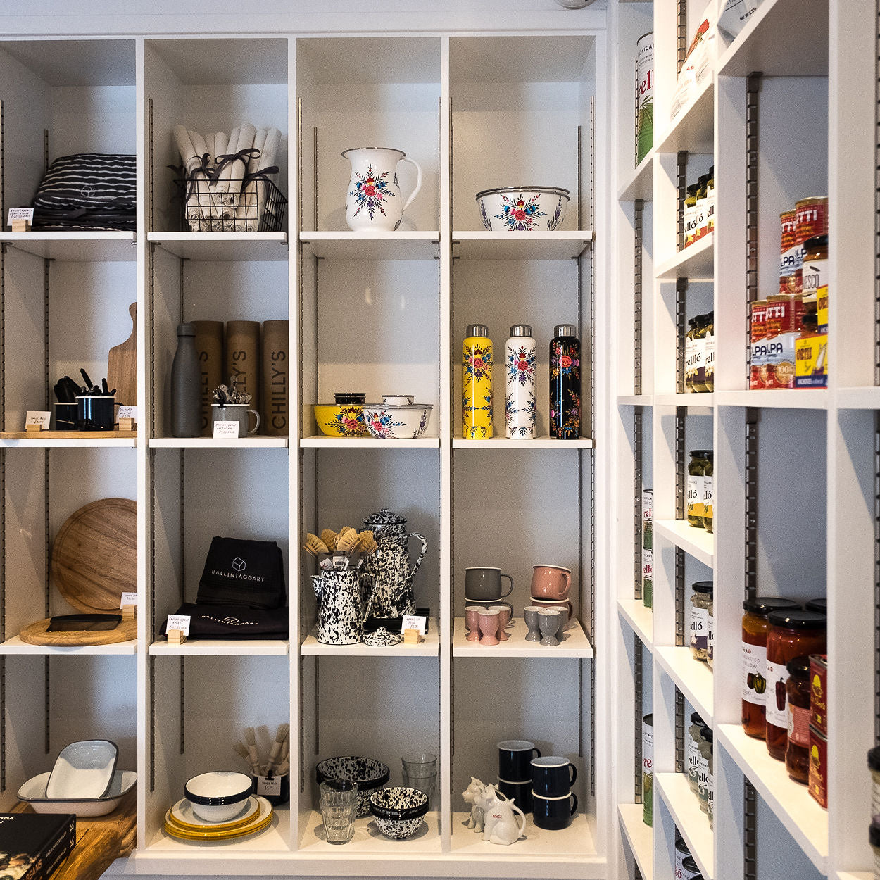 White shelving unit with various decorative items including mugs, bowls, and jars.