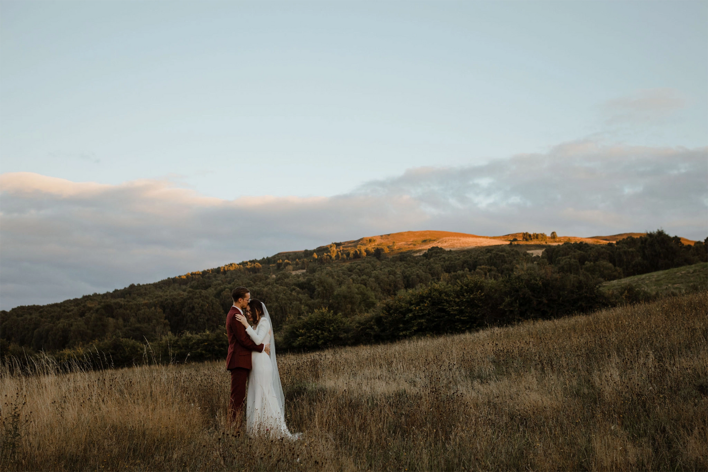 Couple embracing in a field with a scenic background