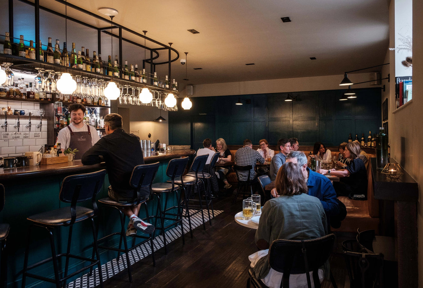People sitting at a bar with drinks and a dark interior.