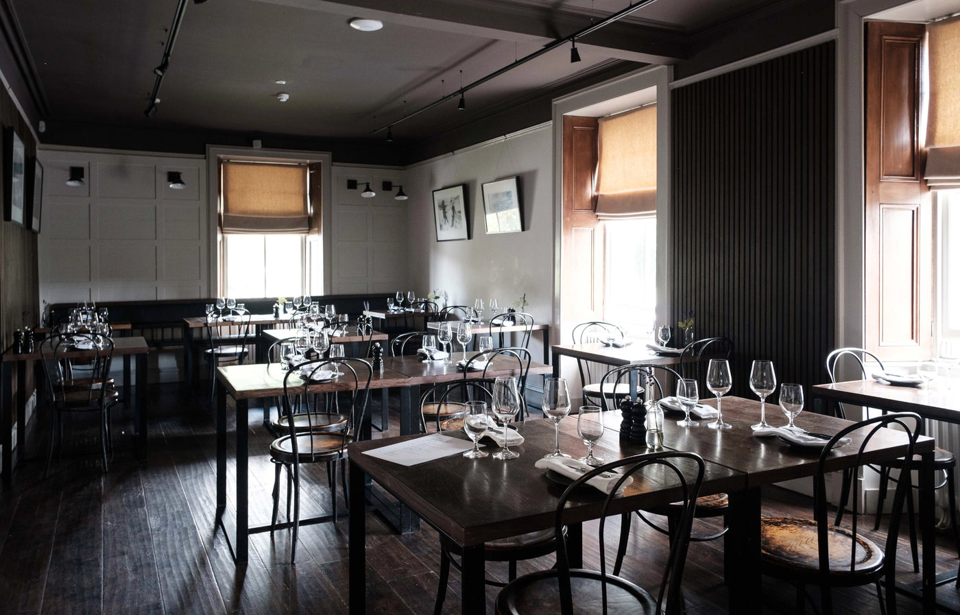 Dining area with tables, chairs, and wine glasses in a restaurant setting.