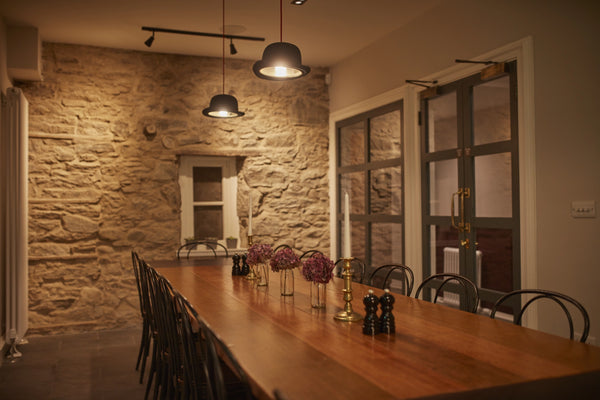 Dining room with wooden table and chairs against a stone wall.