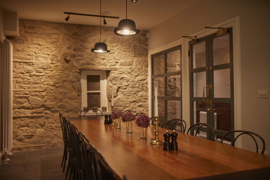 Dining room with wooden table and chairs against a stone wall.