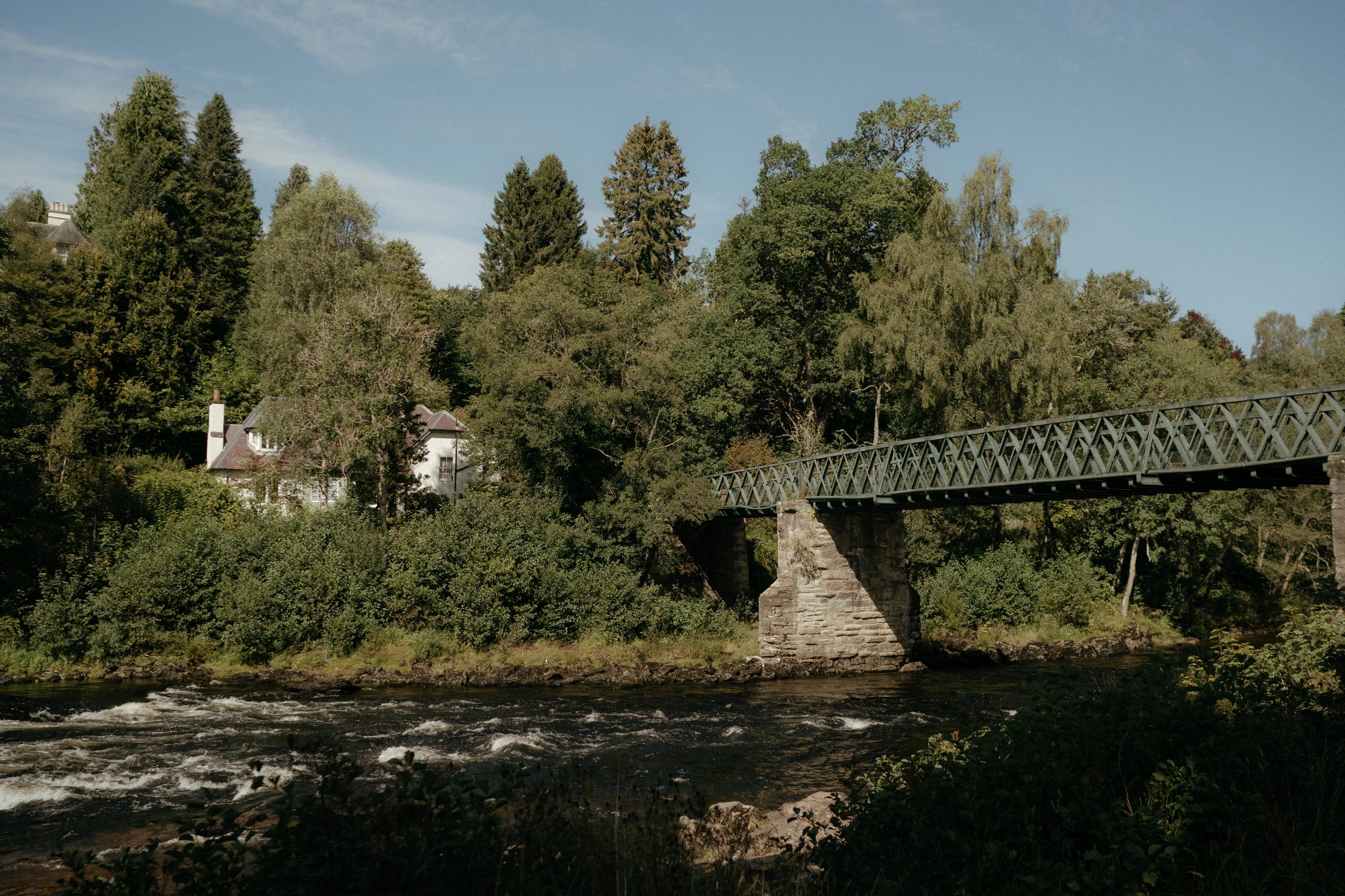 Bridge over a river with trees and buildings in the background