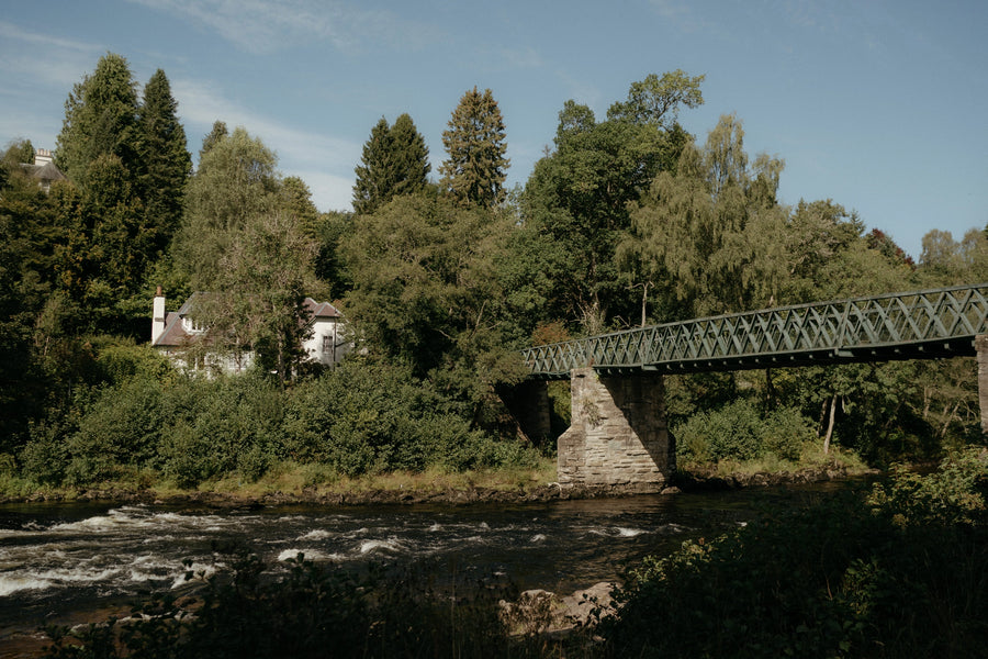 Bridge over a river with trees and buildings in the background